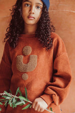 Load image into Gallery viewer, Fleece Pullover in Copper made with 100% organic cotton. The front has an abstract shape in the center. It has a fleecy feel on the inside for extra coziness. Made by Monkind
