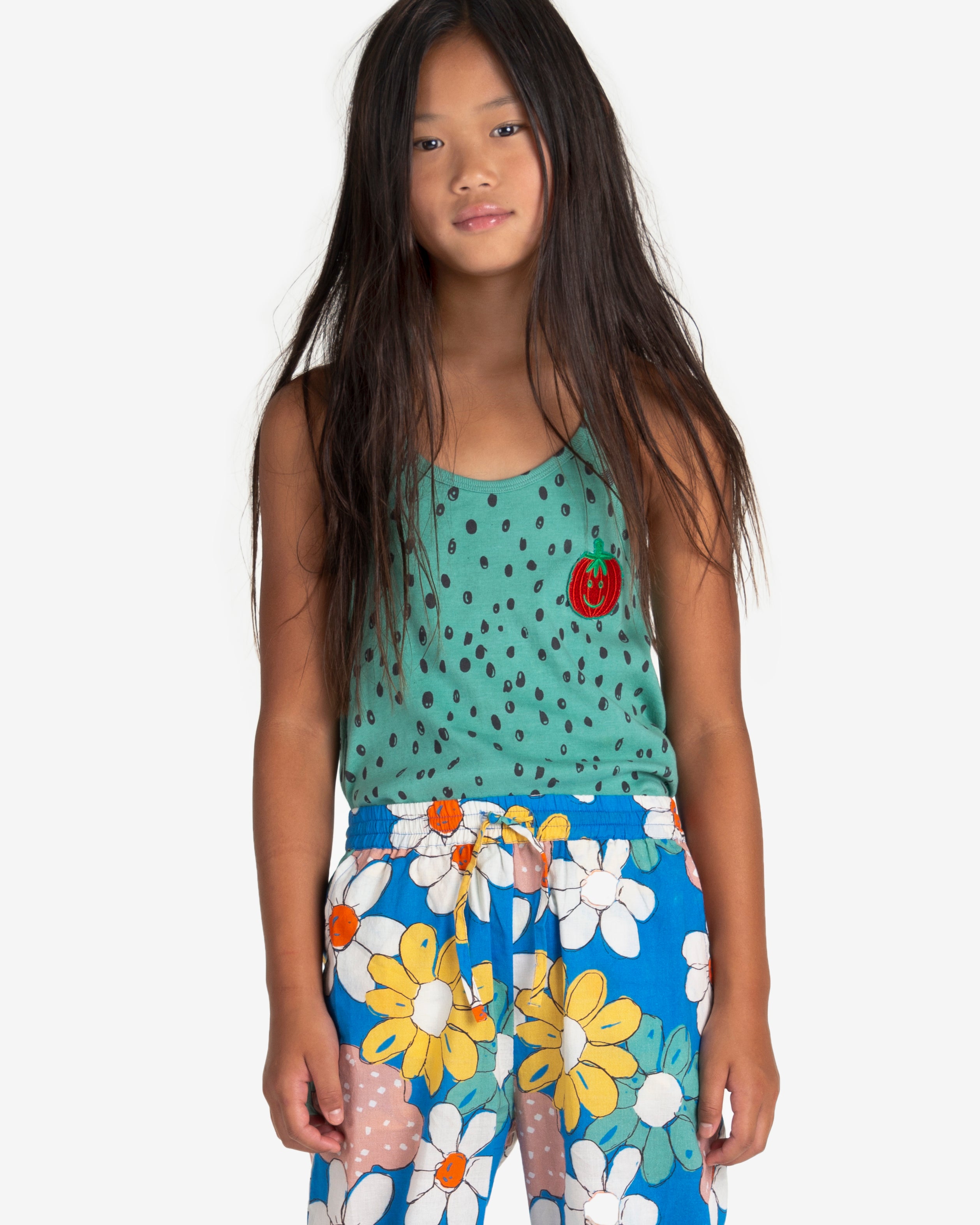 Model wearing Blue trousers with big colourful flowers all-over print. It has an elastic waistband with adjustable cord. It also have two side pockets. nadadelazos