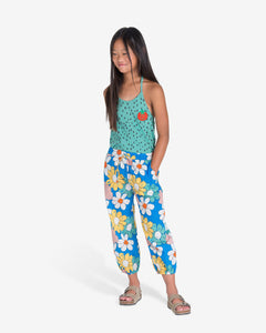 Model wearing Blue trousers with big colourful flowers all-over print. It has an elastic waistband with adjustable cord. It also have two side pockets. nadadelazos