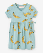Load image into Gallery viewer, Turquoise double-breasted dress with an all-over print of yellow bananas. The wrap detail is fixed and makes the dress very comfy to put on and off. 100% certified organic cotton. 100% pollution-free water print. Made by Nadadelazos
