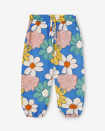 Load image into Gallery viewer, Blue trousers with big colourful flowers all-over print. It has an elastic waistband with adjustable cord. It also have two side pockets. Made by nadadelazos
