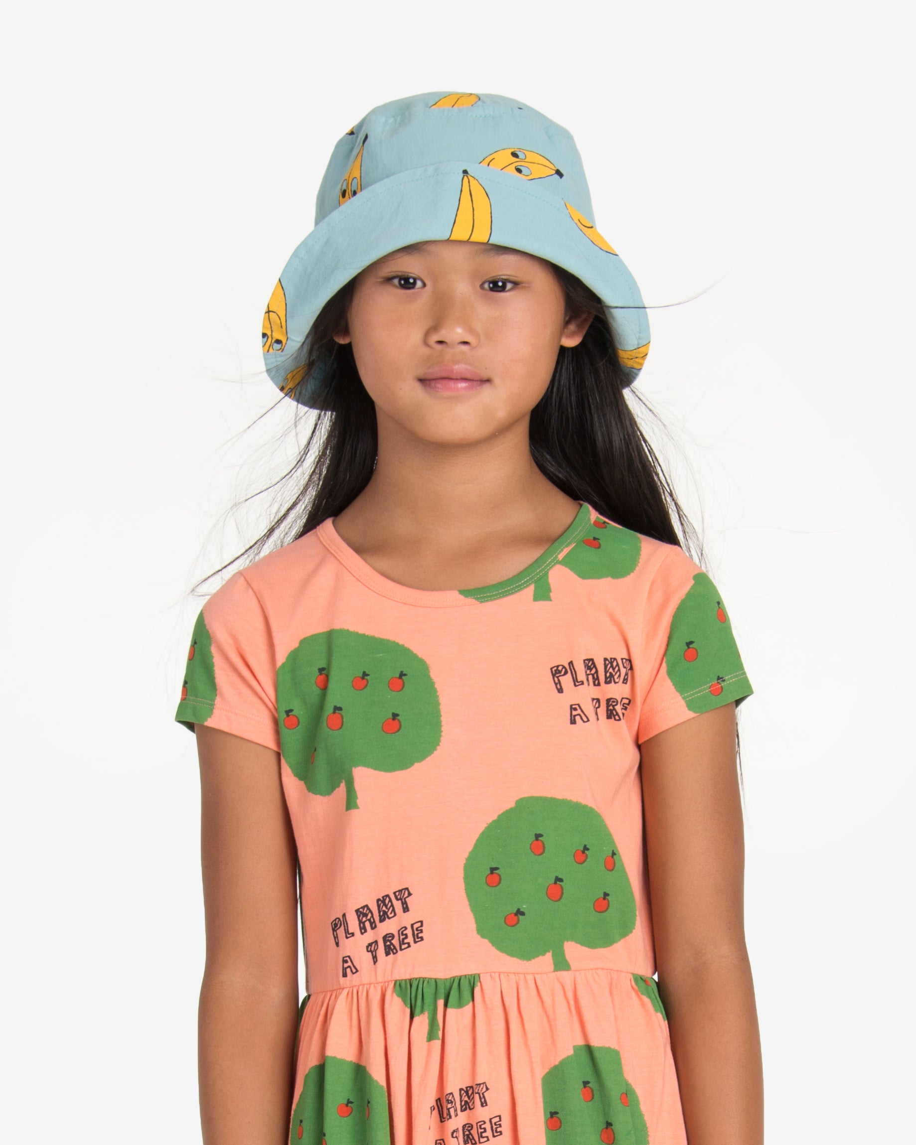 Model wearing a bucket style hat in light green with yellow banana print. Made by Nadadelazos.
