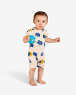 Load image into Gallery viewer, Model wearing Light cream romper with blue clouds and yellow sun print. It comes with a shoulder opening. Made by Nadadelazos
